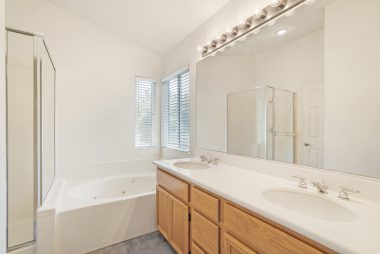 Master bathroom with dual sinks, spa tub, and separate shower.