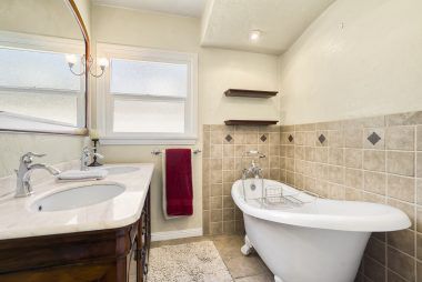 Hall bathroom with tile floors, and claw foot tub with tile surround.