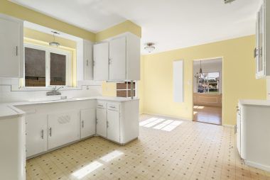 Vintage kitchen with tile counters and breakfast nook with original built-in ironing board, and view into the formal dining room.