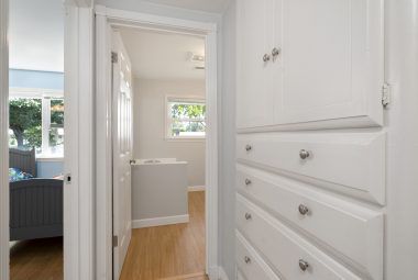 Hallway linen closet with view into front bedroom on left, and hallway bath straight ahead.