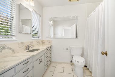 Private master bathroom #1 with shower in tub, large vanity, and tile flooring.