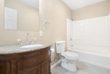 Private master bathroom with granite vanity, new flooring, and shower in tub.