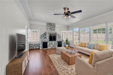 Alternate view of the digitally staged step-down family room with fireplace, ceiing fan, and lots of natural light flowing in from the many windows overlooking the spacious backyard.