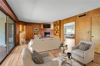 Virtually staged separate family room with fireplace, built-in shelving, privacy pocket doors, and a large sliding glass door overlooking the serene backyard. Brand new laminate flooring too.