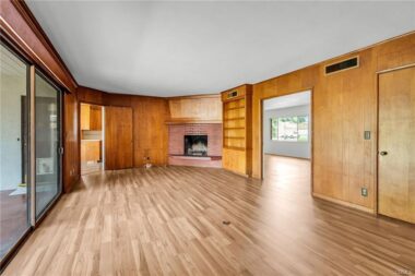 Non-staged separate family room with fireplace, built-in shelving, privacy pocket doors, and a large sliding glass door overlooking the serene backyard. Brand new laminate flooring too.