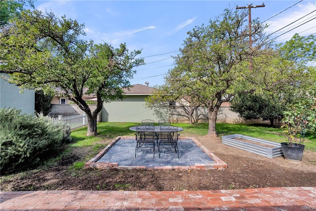 Back section of the yard with an orchard of fruit trees, raised garden bed, shed, greenhouse, and meandering brick pathway through your own private fantasy garden.