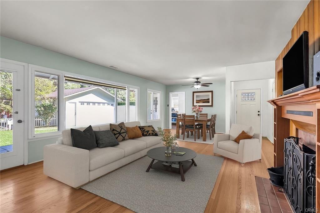 Alternate view of living room and dining room with view through large picture window to the lushly landscaped backyard (Virtually Staged).
