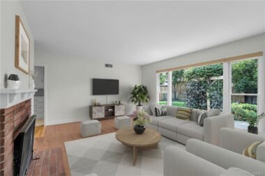 Alternate view of the living room with floor-to-ceiling picture window overlooking the lush backyard with shade trees, rose bushes, fruit trees, and 220 hookup for a spa. (Virtually Staged)