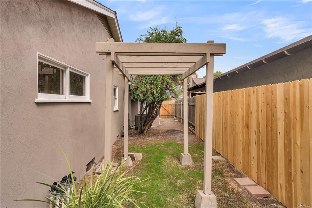 Left side of the house with brand new fence which was stained for preservation, a gazebo, a producing pomegranatae tree, and a gate to the front yard. This area could also be fenced off as a dog-run if needed.
