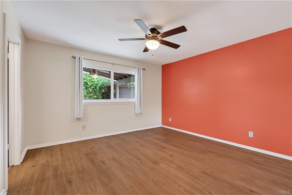 Primary suite with laminate flooring and ceiling fan, as well as new mirrored wardrobe doors on large closet -- original photo.