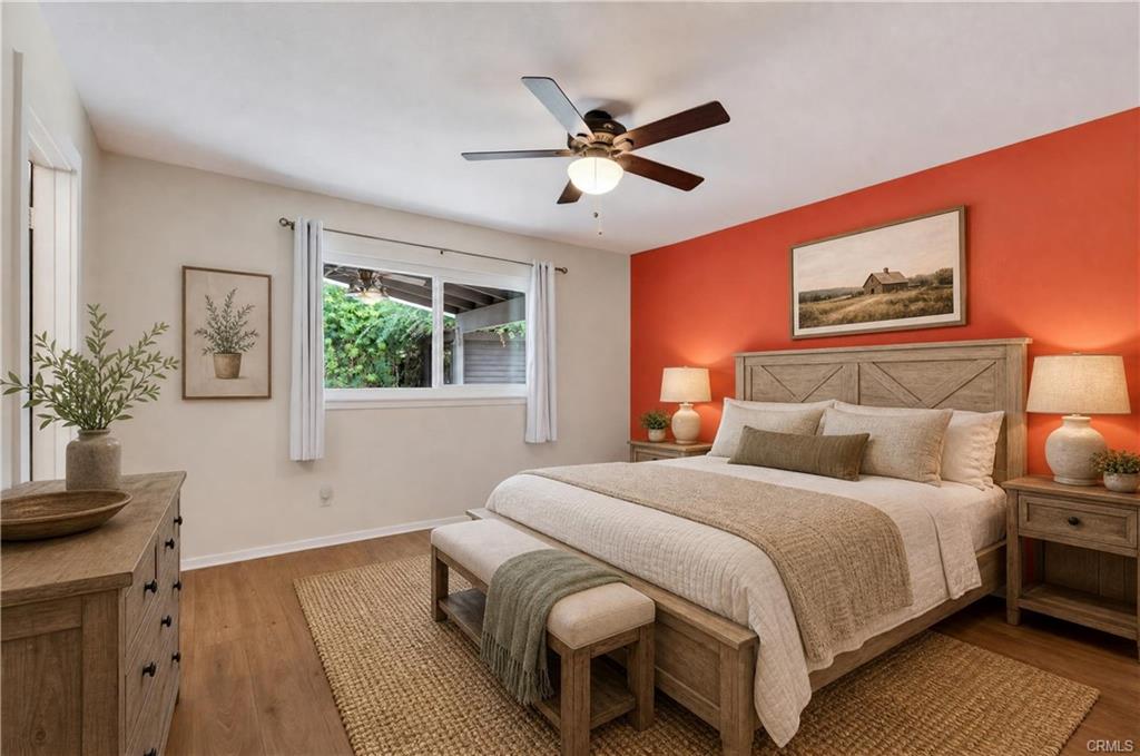 Primary suite with laminate flooring and ceiling fan, as well as new mirrored wardrobe doors on large closet -- virtually staged.