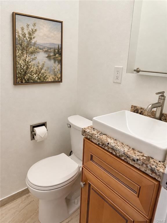 Remodeled half bathroom with granite counter top -- picture on wall was virtually placed.