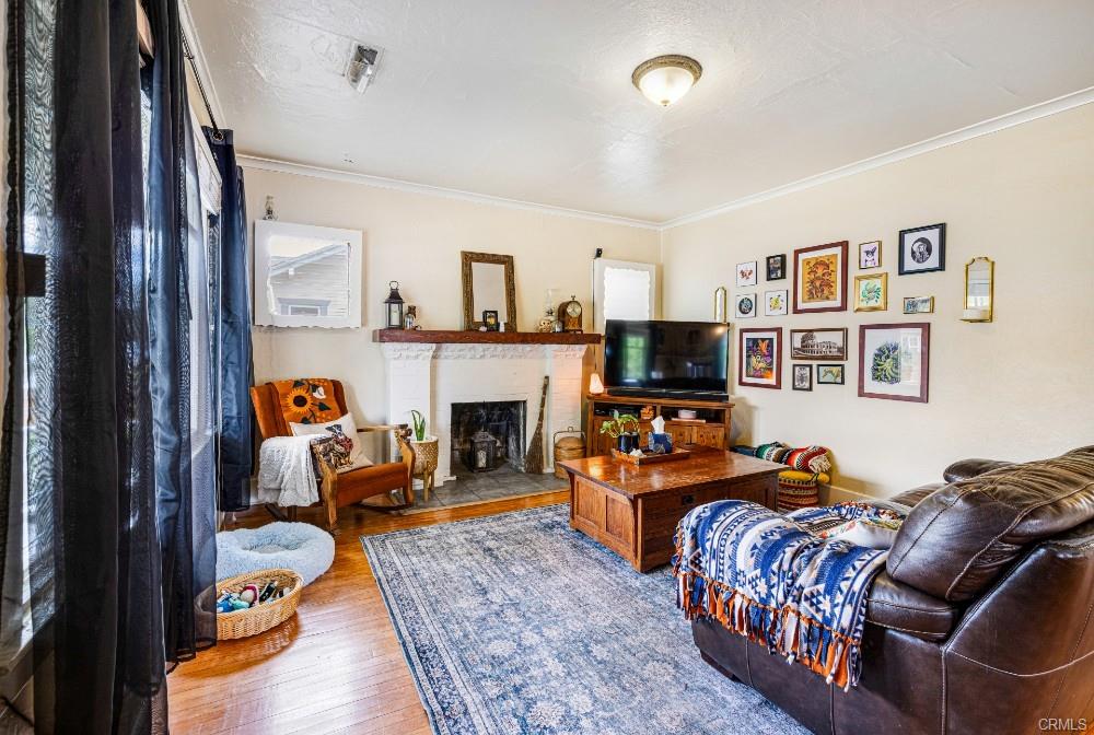 Living room with original hardwood floors and wood-burning fireplace.